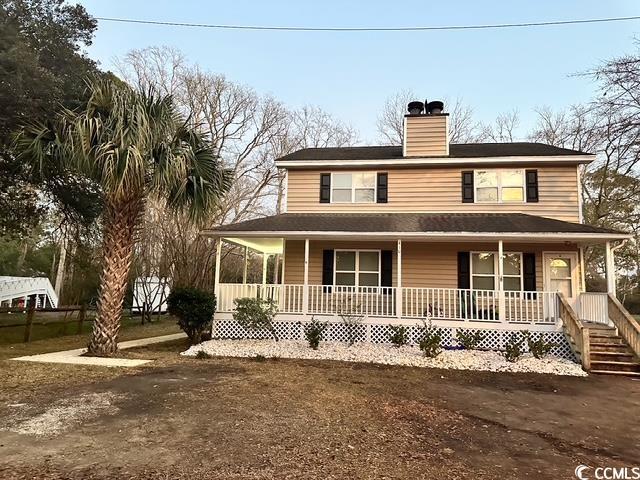 farmhouse-style home featuring a porch and a chimney