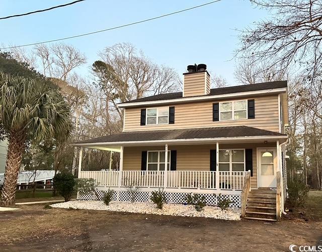 farmhouse featuring a porch and a chimney