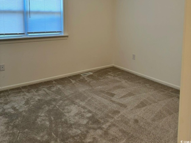 carpeted spare room featuring baseboards and visible vents