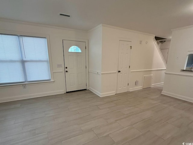 entrance foyer with baseboards, wood finished floors, visible vents, and crown molding