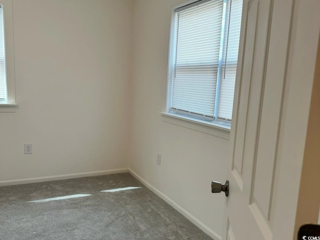 carpeted empty room featuring baseboards