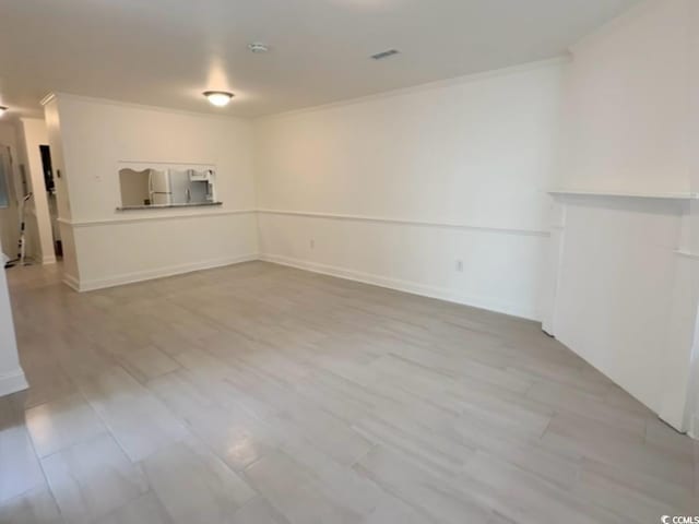 spare room with visible vents, crown molding, baseboards, and wood finished floors