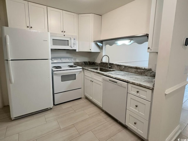 kitchen with white appliances, white cabinetry, and a sink