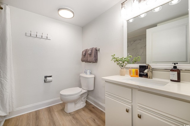 bathroom featuring wood finished floors, a shower with shower curtain, toilet, vanity, and baseboards