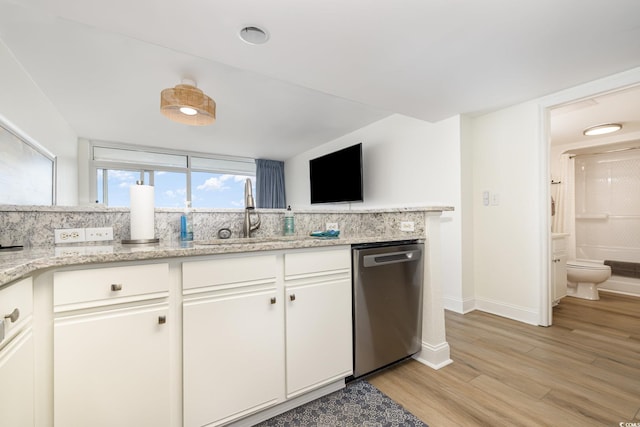 kitchen featuring light wood finished floors, a sink, baseboards, stainless steel dishwasher, and white cabinets