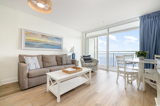 living area featuring floor to ceiling windows, light wood-style flooring, and baseboards