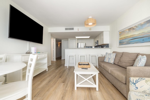 living area with visible vents and light wood-style floors