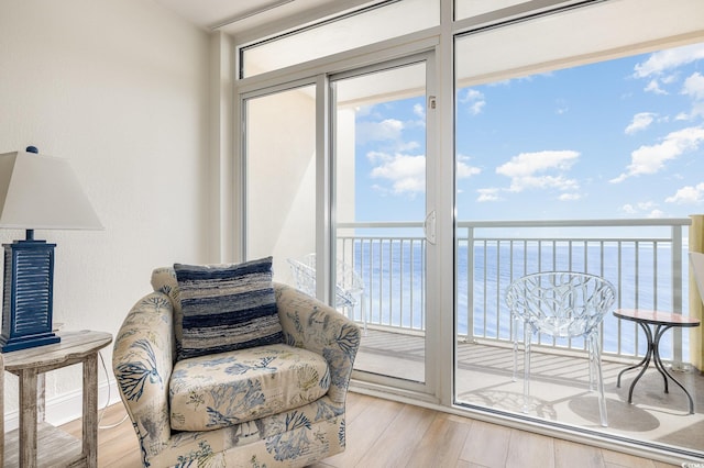 sitting room featuring a water view, a wealth of natural light, and wood finished floors