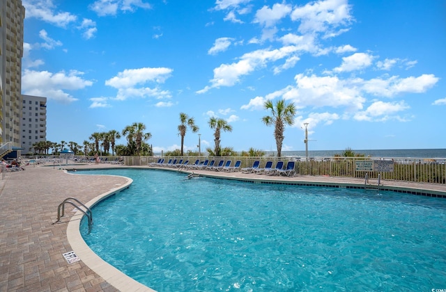 community pool with a patio area and fence