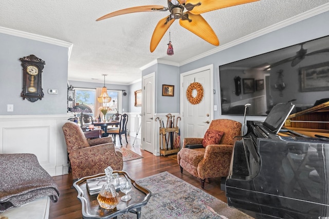 living area featuring a wainscoted wall, a textured ceiling, wood finished floors, and ornamental molding