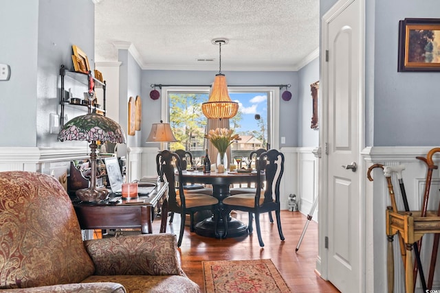 dining area featuring crown molding, wood finished floors, and wainscoting