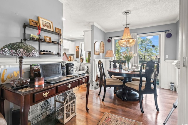 dining area with visible vents, ornamental molding, a textured ceiling, wood finished floors, and wainscoting