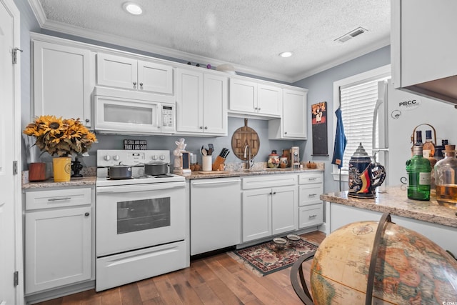 kitchen with white appliances, dark wood-style floors, visible vents, ornamental molding, and white cabinets