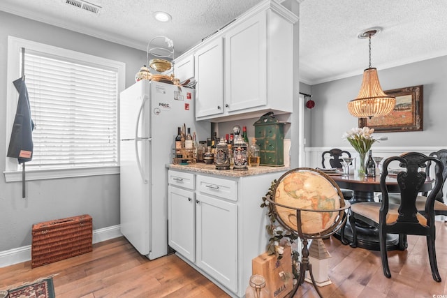 kitchen featuring light wood-style flooring, a textured ceiling, white cabinetry, freestanding refrigerator, and crown molding