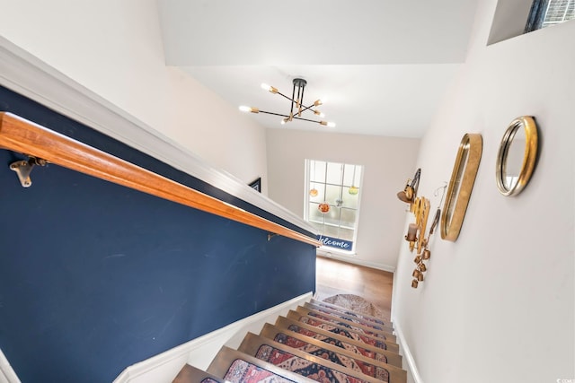 stairway with baseboards and a notable chandelier