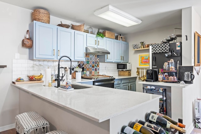 kitchen with decorative backsplash, a peninsula, stainless steel electric stove, under cabinet range hood, and a sink