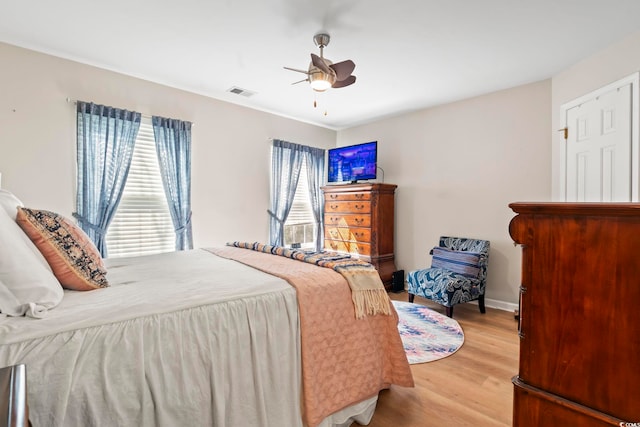 bedroom featuring baseboards, light wood-style flooring, visible vents, and a ceiling fan