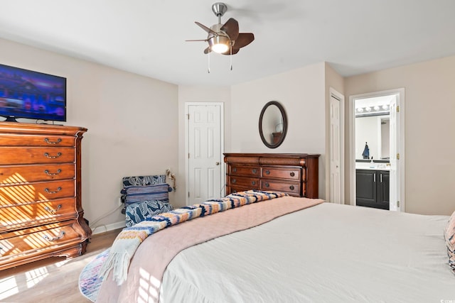 bedroom with ceiling fan, connected bathroom, a sink, wood finished floors, and baseboards