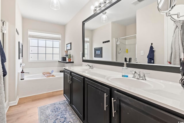 bathroom featuring a garden tub, wood finished floors, a sink, and visible vents