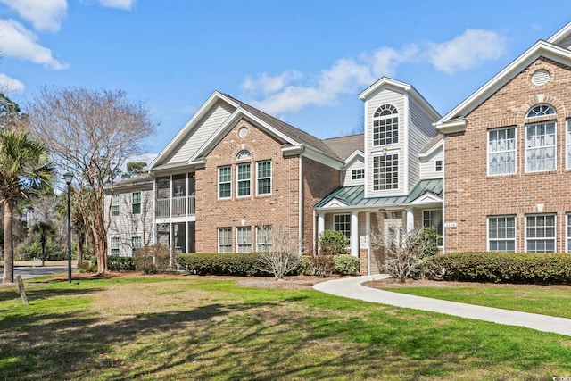 view of front of home featuring brick siding, a standing seam roof, and a front yard