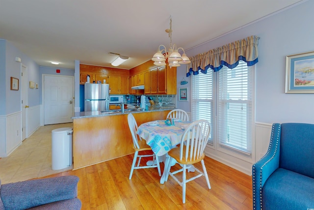 dining space featuring a chandelier, wainscoting, visible vents, and light wood-style floors