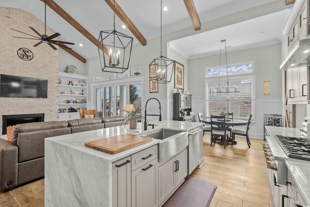 kitchen featuring a large fireplace, white cabinetry, appliances with stainless steel finishes, high vaulted ceiling, and a sink