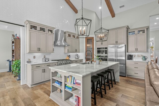 kitchen featuring visible vents, a sink, wall chimney range hood, beamed ceiling, and stainless steel appliances