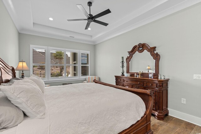 bedroom featuring baseboards, recessed lighting, dark wood-type flooring, a tray ceiling, and ceiling fan