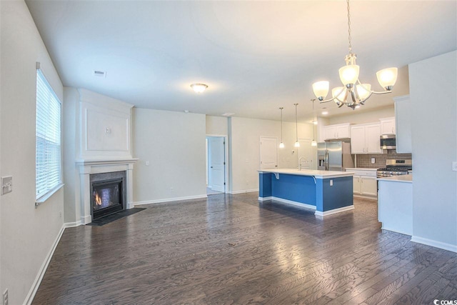 kitchen with dark wood-type flooring, a breakfast bar area, light countertops, appliances with stainless steel finishes, and white cabinets