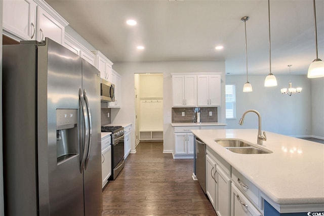 kitchen with a center island with sink, a sink, decorative backsplash, appliances with stainless steel finishes, and white cabinetry