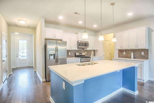 kitchen featuring a center island with sink, dark wood-style flooring, a sink, white cabinets, and appliances with stainless steel finishes