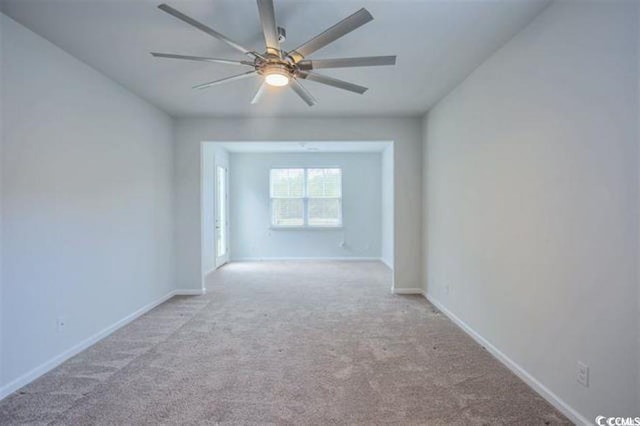 carpeted spare room featuring baseboards and ceiling fan