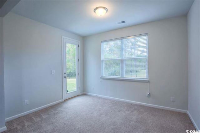 carpeted spare room with visible vents, baseboards, and a healthy amount of sunlight