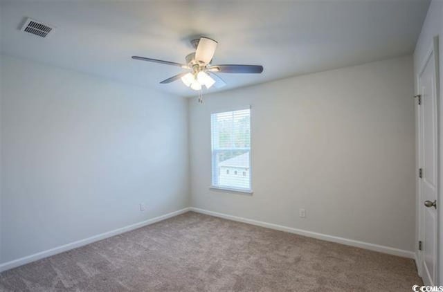 carpeted empty room featuring baseboards, visible vents, and ceiling fan