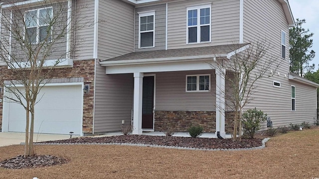 view of front of house with stone siding, an attached garage, and a shingled roof