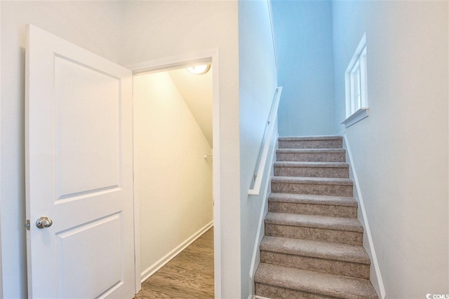 staircase featuring wood finished floors and baseboards