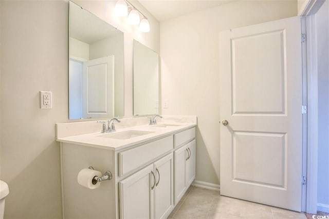 bathroom featuring double vanity, tile patterned flooring, baseboards, and a sink