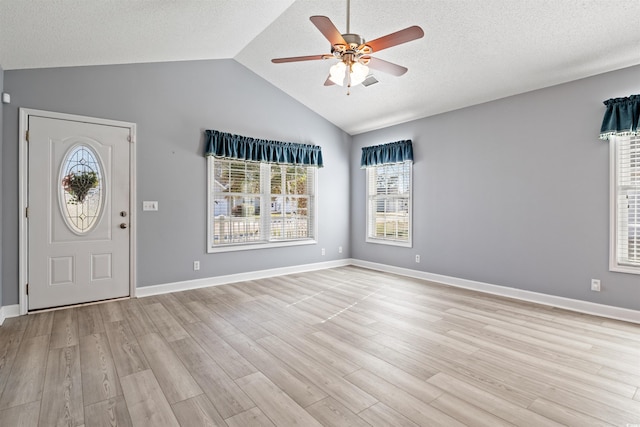 foyer entrance featuring lofted ceiling, a textured ceiling, light wood-type flooring, and a ceiling fan