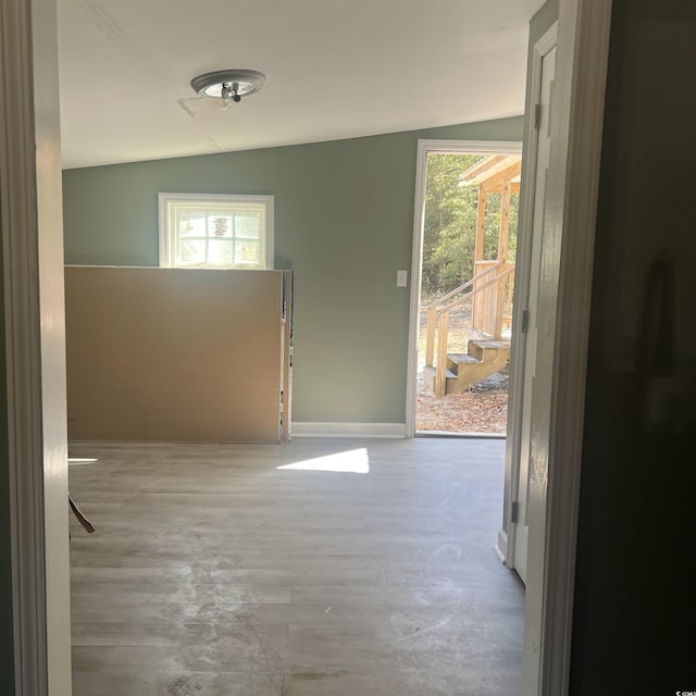 hall featuring lofted ceiling, wood finished floors, and baseboards