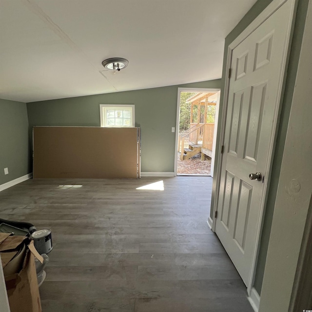 interior space featuring baseboards, wood finished floors, and vaulted ceiling