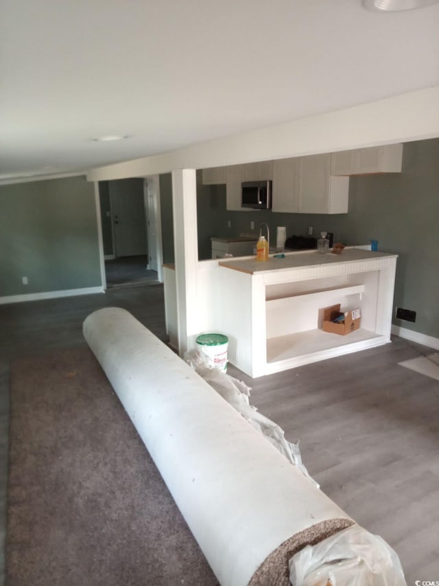 kitchen with stainless steel microwave, wood finished floors, and baseboards