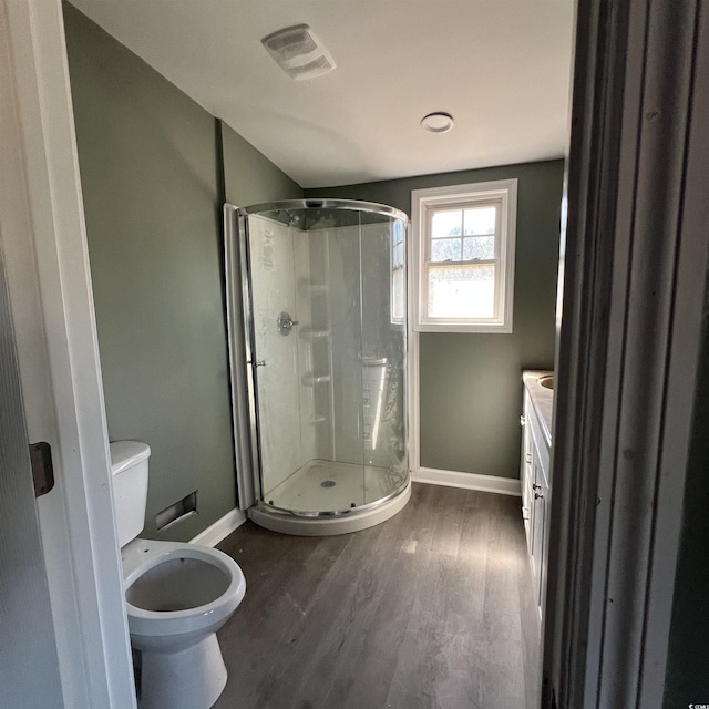 bathroom featuring visible vents, toilet, a stall shower, wood finished floors, and baseboards