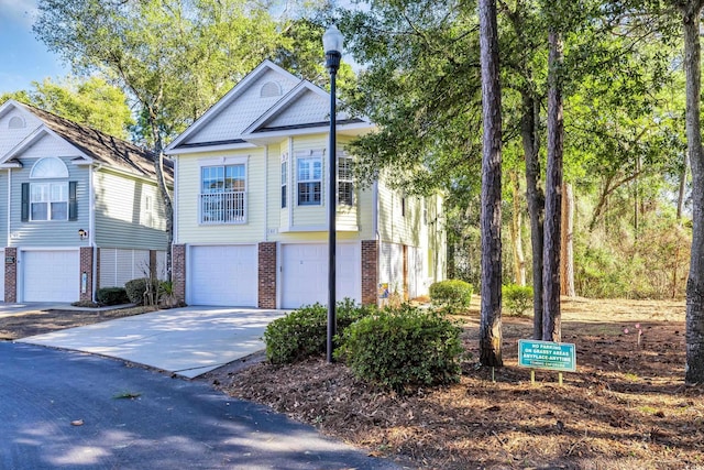 view of front of property featuring a garage, driveway, and brick siding