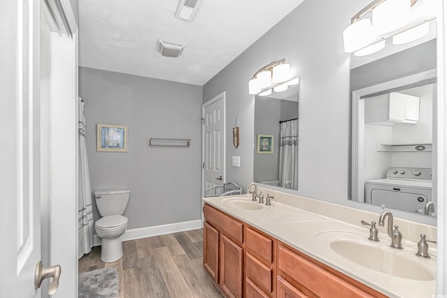 full bath featuring wood finished floors, washer / clothes dryer, a sink, and toilet