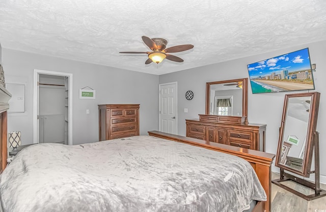 bedroom featuring a textured ceiling, a ceiling fan, and wood finished floors