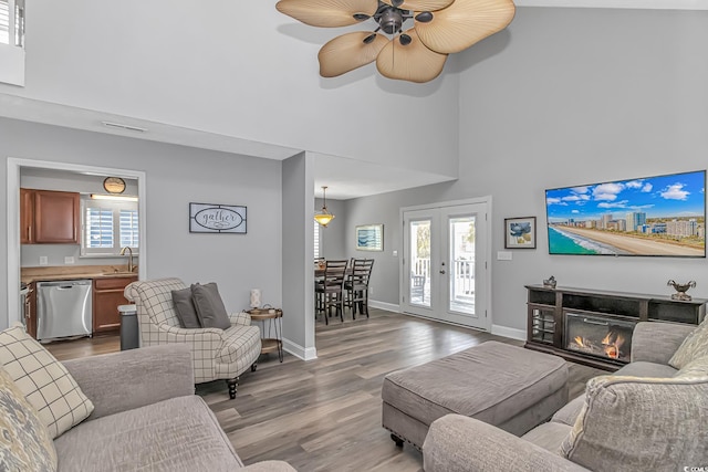 living area with a glass covered fireplace, a healthy amount of sunlight, baseboards, and wood finished floors