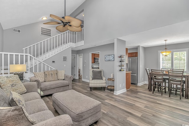 living area with light wood-style floors, visible vents, stairway, and baseboards