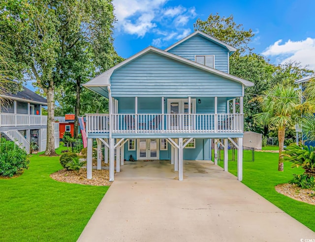 raised beach house featuring french doors, stairway, a front yard, a carport, and driveway