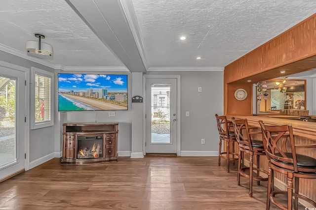 interior space with ornamental molding, a dry bar, a textured ceiling, and wood finished floors