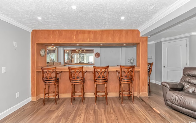 bar with ornamental molding, a textured ceiling, baseboards, and wood finished floors